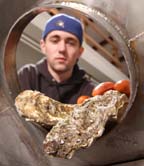 Brandon Spry puts oysters into a giant canister for processing.